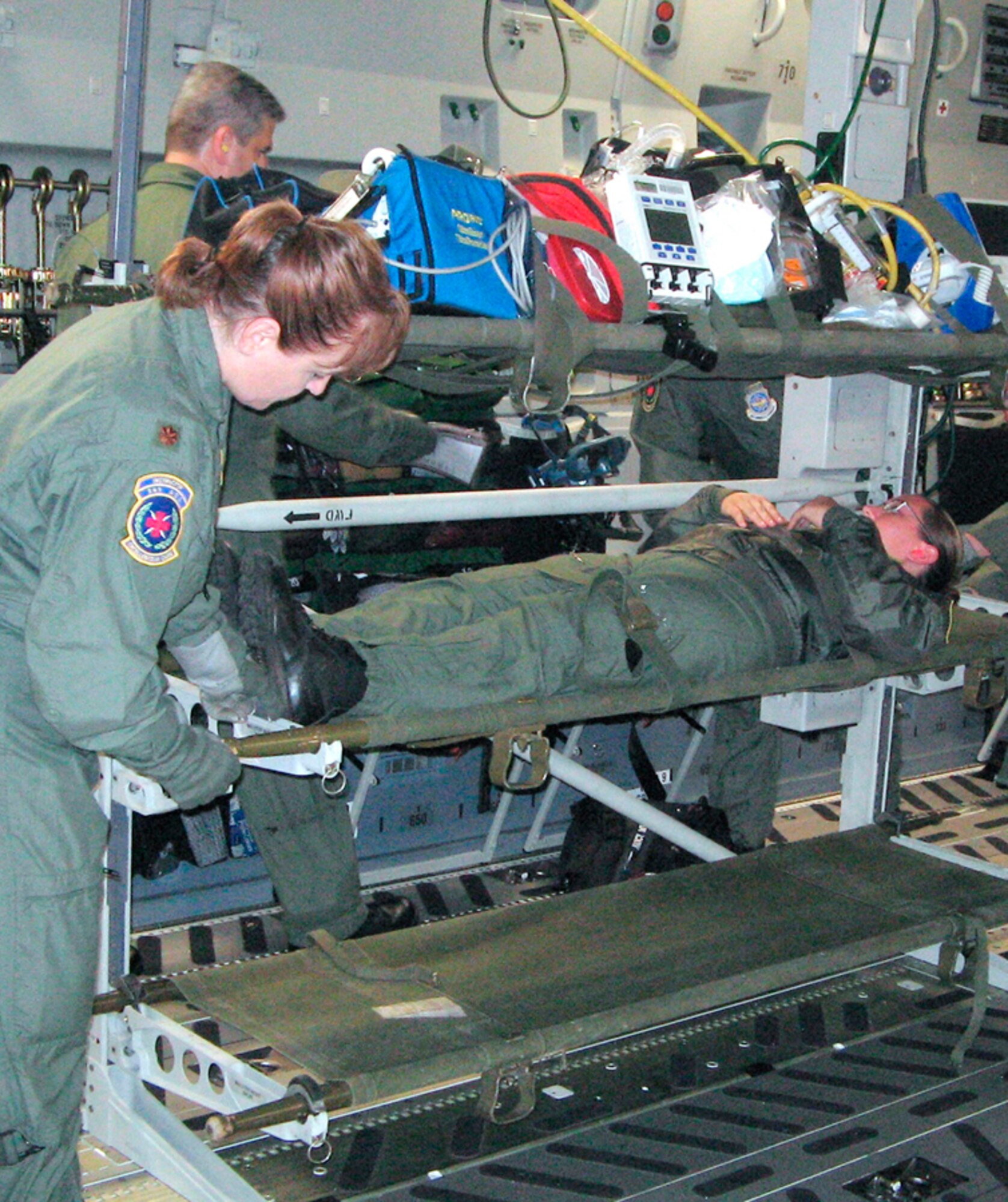 Teamwork:  Maj. Andrea Cornett, 349th Aeromedical Evacuation Squadron, is securing patient, Senior Airman Courtney Johnson, 349th AES, in the C-17 litter stanchion while Technical Sgt. Paul Rogers, 349th AES, is connecting medical equipment.