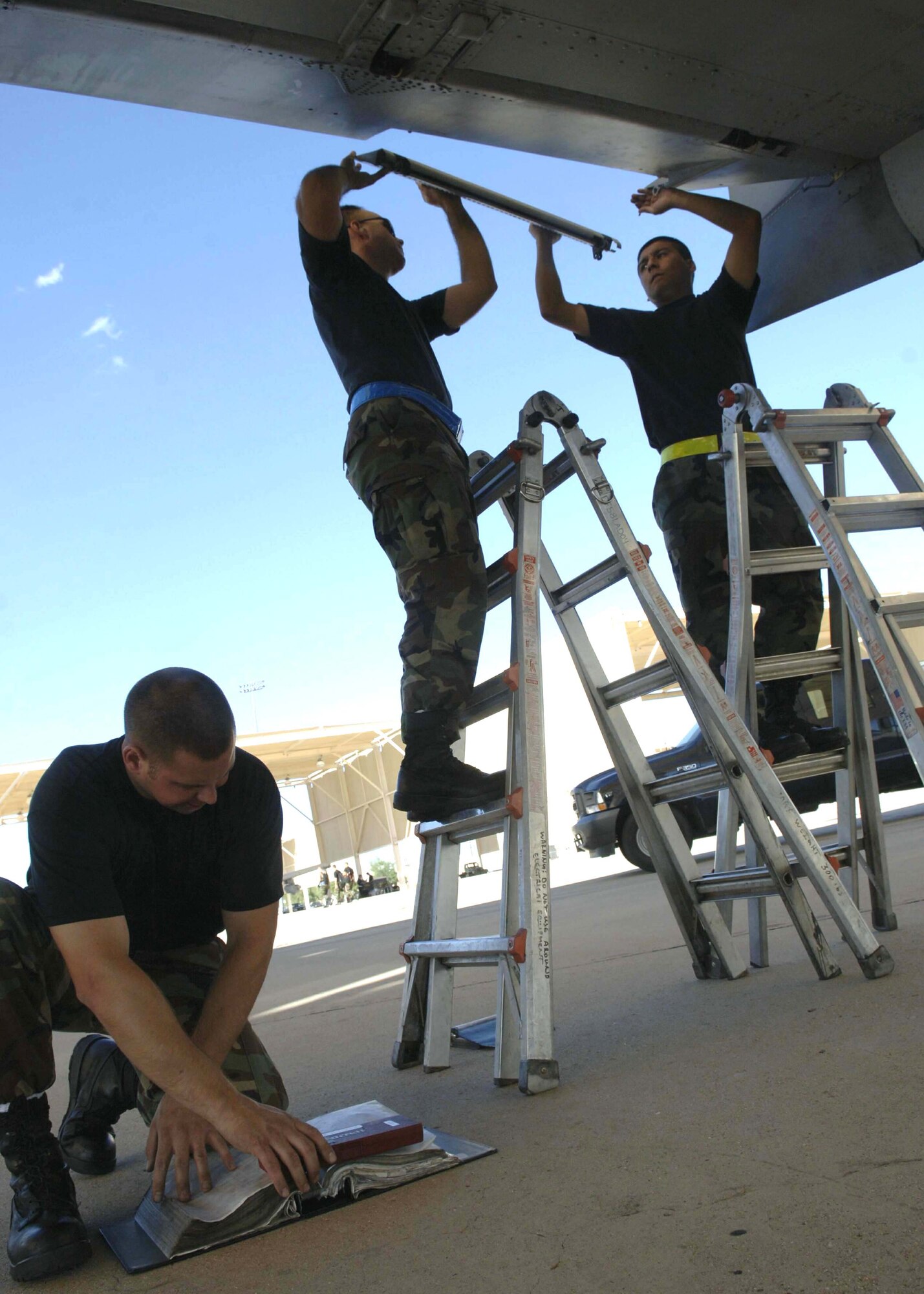 Staff Sgt. Michael Marsh refers to a technical order while Staff Sgts. Erick Diaz and Moses Davenport perform maintenance on an A-10 Thunderbolt II during Exercise Bushwacker 06-04 Sept. 15 at Davis-Monthan Air Force Base, Ariz. (U.S. Air Force photo/Senior Airman Christina D. Ponte)