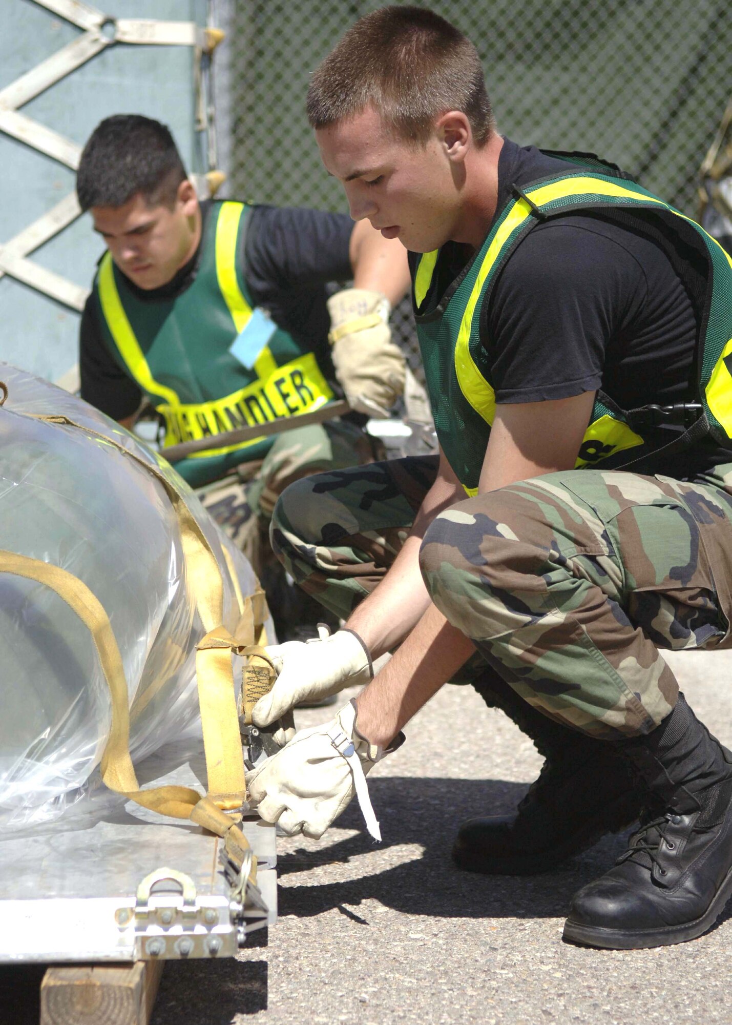 Airman 1st Class Jeff Nobel and Senior Airman Juan Hernandez secure a net onto a pallet during Exercise Bushwacker 06-04 Sept. 15 at Davis-Monthan Air Force Base, Ariz. Airman Nobel is with the 355th Equipment Maintenance Squadron and Airman Hernandez is with the 355th Services Squadron. (U.S. Air Force photo/Senior Airman Christina D. Ponte)