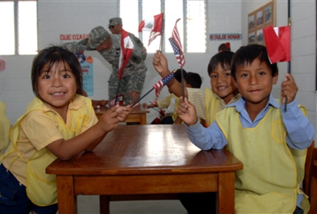 Children wave American and Peruvian flags during an opening ceremony for a new school built by Navy Seabees during New Horizons 06 in Hornitos, Peru, Sept. 15, 2006. New Horizons is a humanitarian assistance exercise.
