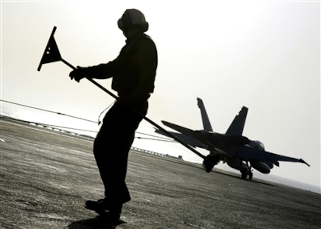 A U.S. sailor guides the arresting wire as it retracts after an arrested landing of an F/A-18C Hornet aboard the nuclear-powered aircraft carrier USS Enterprise in the Arabian Sea, Sept. 19, 2006.  