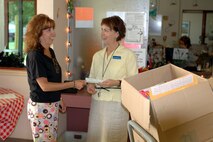 Mrs. Deb Arquiette, [left] wife of Col. Steve Arquiette, 60th Air Mobility Wing commander, hands over a check for $1,000 to Mrs. Nancy Kawata, Travis School principal at Travis Air Force Base, Calif. (U.S Air Force photo by Staff Sgt. Matt McGovern / 60th AMW Public Affairs)
