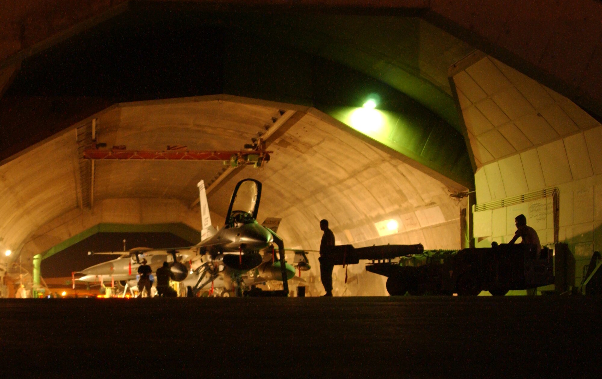 Weapons loaders from the 332nd Expeditionary Aircraft Maintenance Squadron at Balad Air Base, Iraq, wait outside a hardened aircraft shelter for a maintainer's signal to proceed with the weapons load on a newly arrived Guard F-16 Fighting Falcon from Michigan Sept. 20. (U.S. Air Force photo/Senior Airman Kerry Solan-Johnson)