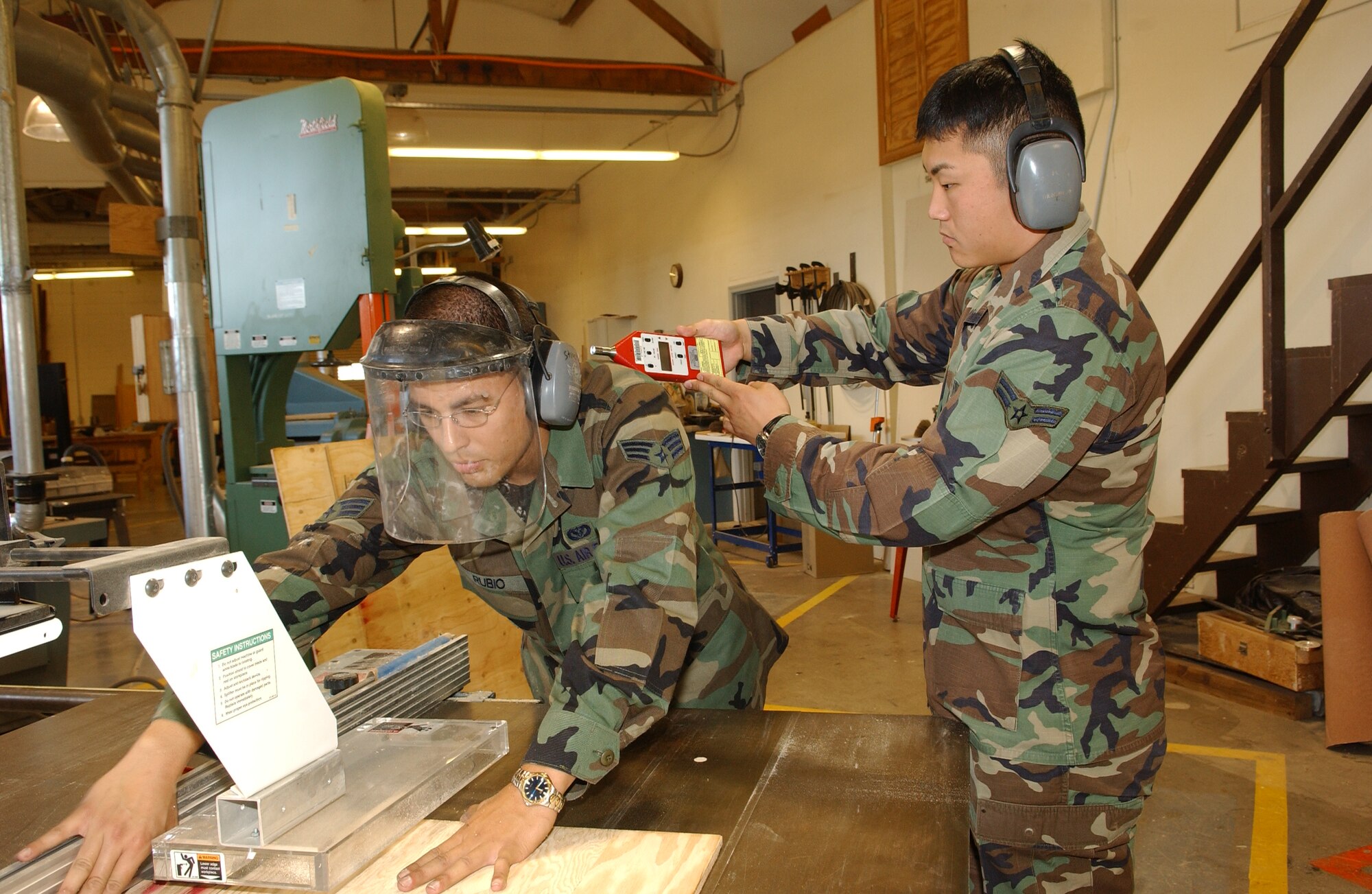 MCCHORD AIR FORCE BASE, Wash. — Airman Strain takes a noise-level reading while Senior Airman Camilo Rubio, 62nd Civil Engineer Squadron, cuts a piece of plywood. (U.S. Air Force photos/Abner Guzman)