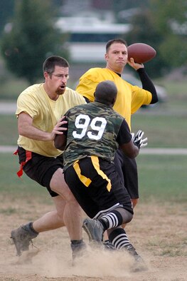 868th Communications Squadron quarterback, Jason Ham, throws a touchdown pass as team mate William Paterson provides protection from 375th Logistics Readiness Squadron pass rusher during recent Intramural Flag Football action. The Communicators from the 868th defeated LRS in a close defensive battle 7-0.  
Photo by Marv Lynchard