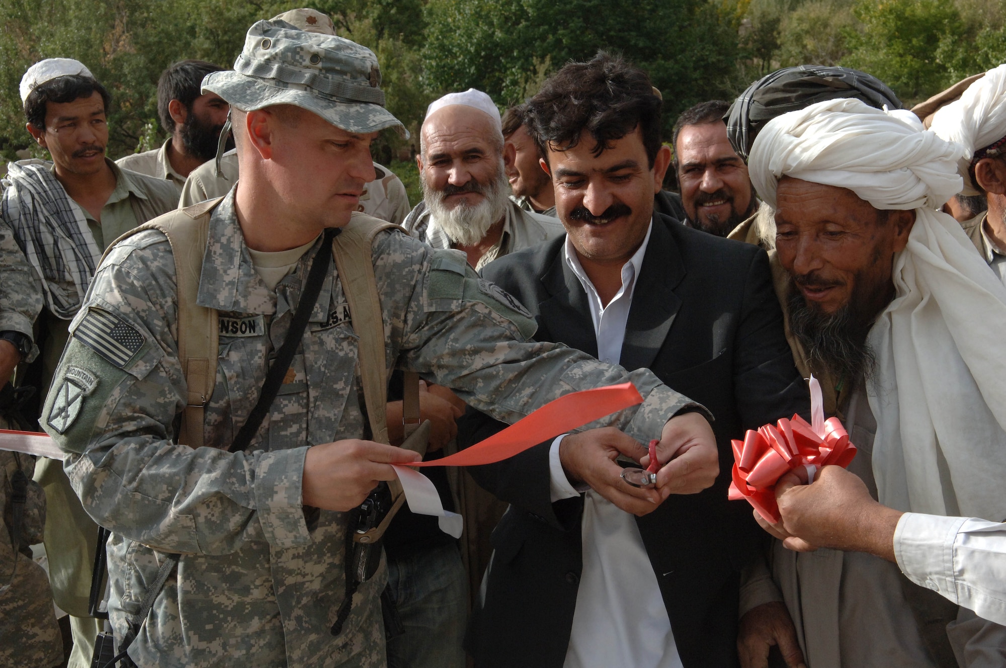 Army Major Don Johnson, Bagram PRT team leader, cuts the ribbon officially opening a new bridge in the Parwan province of Afghanistan.  Major Johnson is accompanied by the contractor and village chief.  This bridge is one of two that were opened recently during a three day mission to the province to assess several on-going construction projects.  (U.S. Air Force photo/Tech. Sgt. Joseph Kapinos)