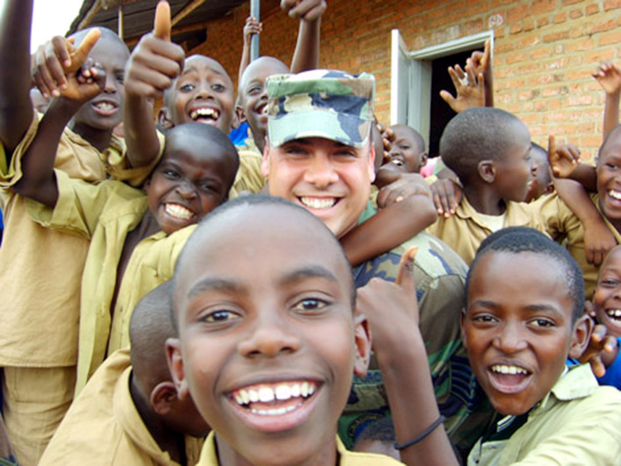 Schoolchildren surround Tech. Sgt. Hector Nieves at their Kigali, Rwanda, school where Airmen from Ramstein Air Base, Germany, delivered school supplies, blankets and clothing donated by the Kaiserslautern Military Community. Sergeant Nieves is assigned to the 86th Air Mobility Squadron. (U.S. Air Force photo/Senior Airman David O'Leary) 

