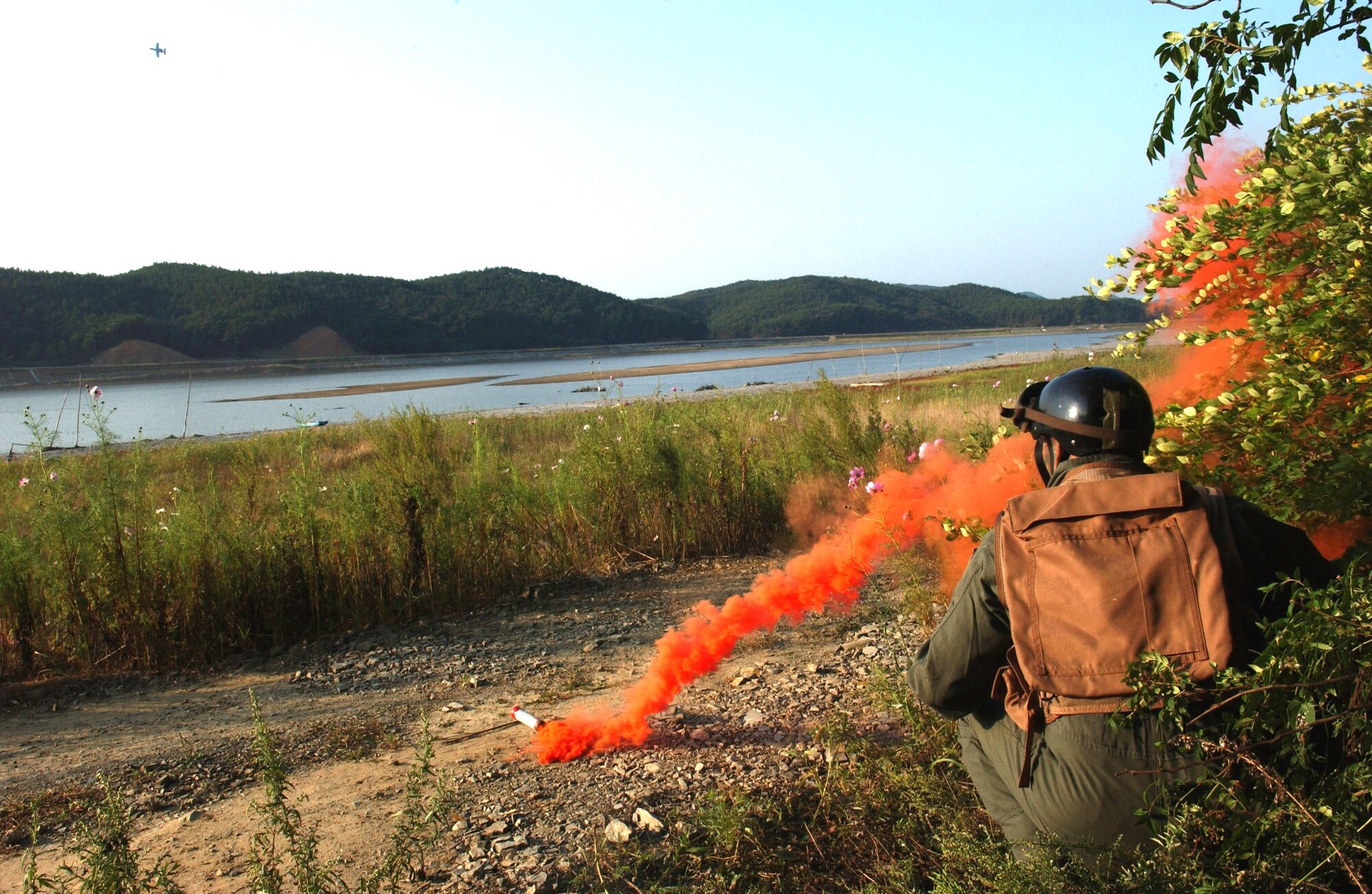 Maj. Paul Neidhardt gets the attention of four A-10 Thunderbolt II pilots by using a smoke grenade during combat search and rescue training Sept. 21 near Osan Air Base, South Korea. Annual training is conducted by survival, evasion, resistance and escape instructors to reacquaint aircrew members with combat search and rescue procedures and techniques. Major Neidhardt is with the 25th Fighter Squadron at Osan AB.  (U.S. Air Force photo/Airman 1st Class Chad Strohmeyer)

