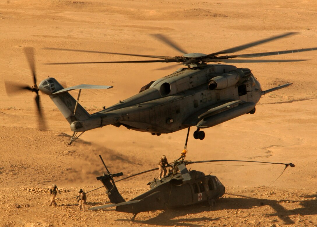 Marines with the Helicopter Support Team prepare to hook the immobilized UH-60 Blackhawk to the CH-53E Super Stallion hovering over them in the Al Anbar Province of Iraq, Sept. 27. The Blackhawk was disabled earlier in the week when it landed during a routine training mission. It was successfully recovered by Marine Heavy Helicopter Squadron 361, Marine Aircraft Group 16 (Reinforced), 3rd Marine Aircraft Wing (Forward). The Helicopter Support Team is with Combat Logistics Company 111, Combat Logistics Battalion 1, 1st Marine Logistics Group (Forward).