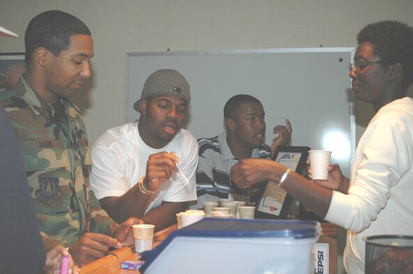Amn Mitch Burns and SrA Evan Pipkins sample drinks at the coffee bar while Airman First Class Latoya Scott bartends.