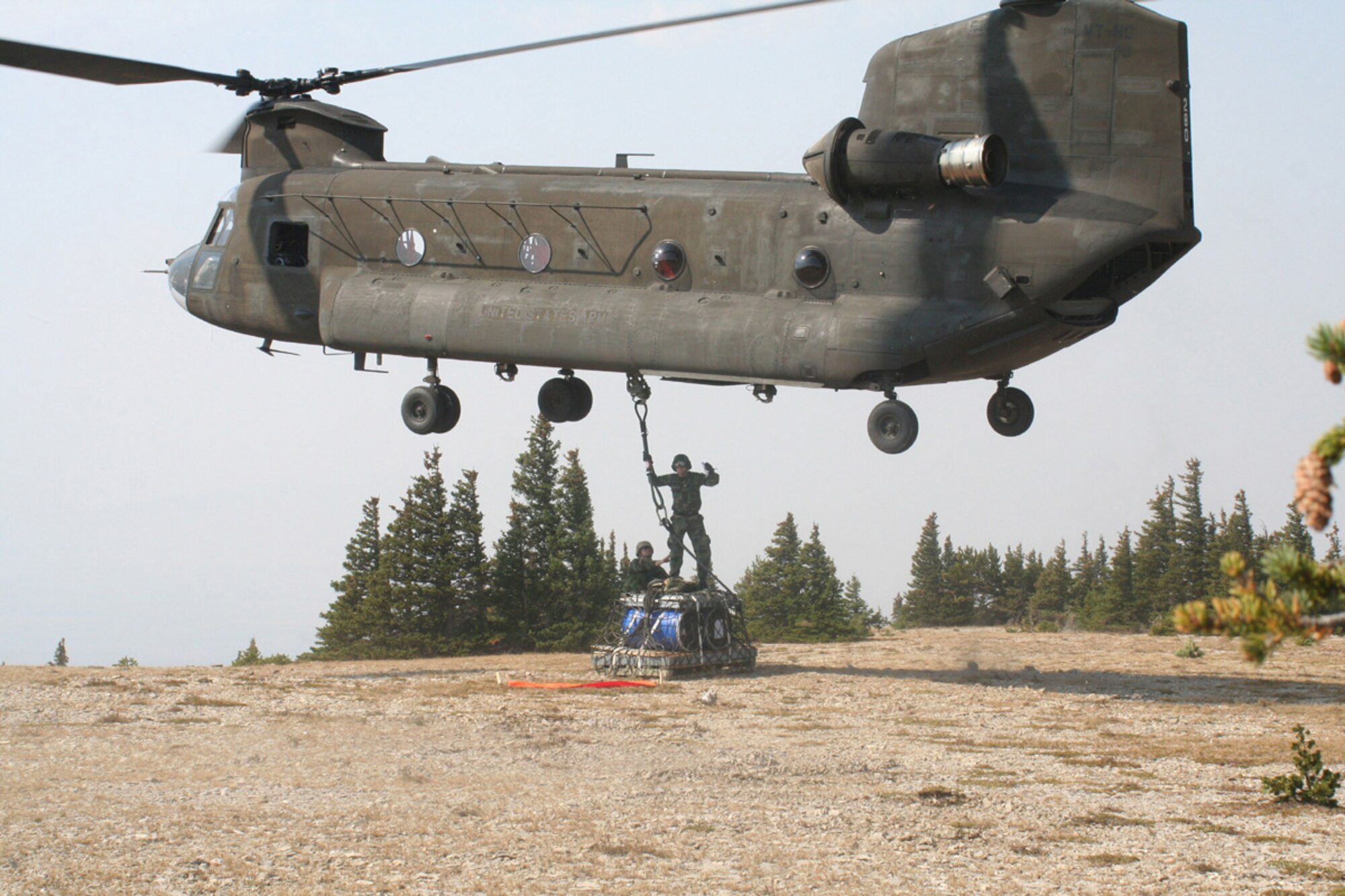 Senior Airman Jared Pahutski and Tech. Sgt. Todd Pederson, 819th Airborne RED HORSE members, hook up the final load of debris to be flown off West Peak near the town of Judith Gap, Mont., as part of a project to restore an outdated monitoring site to its original condition. 