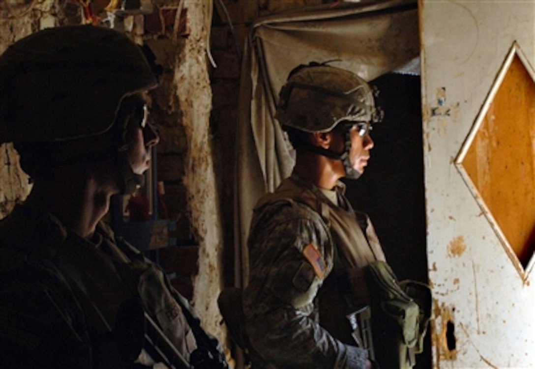 U.S. Army soldiers from Charlie Company, 1st Battalion, 17th Infantry Regiment, 172nd Stryker Brigade Combat Team provide security as fellow soldiers search the backyard of a home in Baghdad, Iraq, Sept. 23, 2006. 