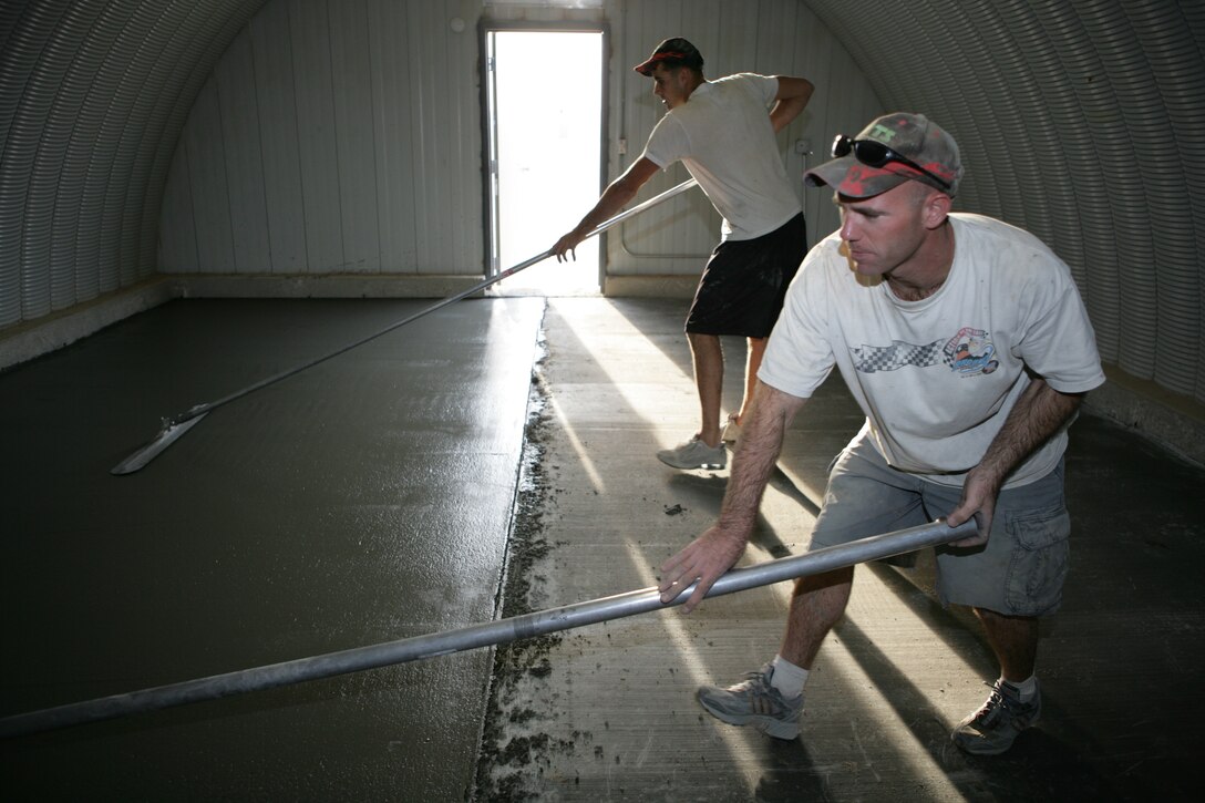 Making sure the cement surface is smooth, Staff Sgt. Kevin Ferree and Cpl. Philip Schreffler work over a freshly poured concrete slab inside of a unit living area at Camp Wilson.  Over 10 days, the pair have poured more than 1,000 cubic yards of concrete into 10 buildings where Marines live while going through Mojave Viper training.