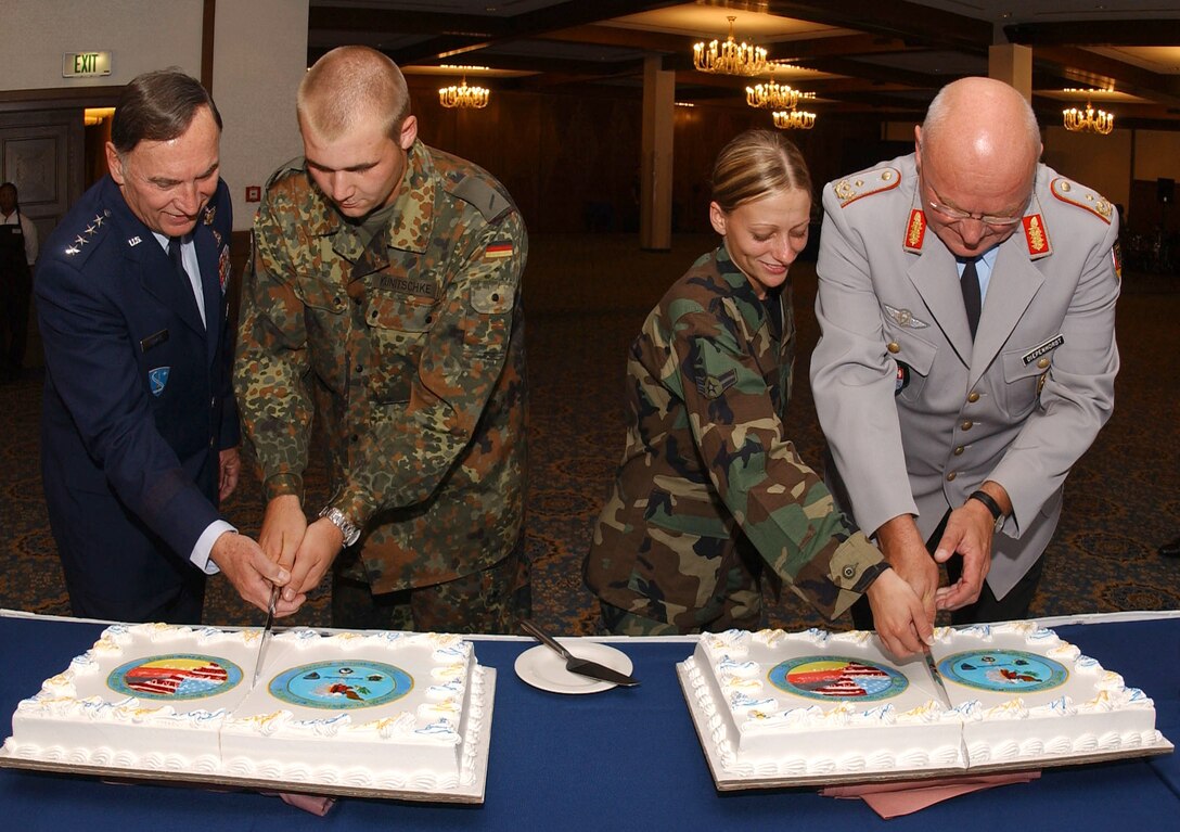 (Left to right) Gen. William T. Hobbins, U.S. Air Forces in Europe commander; Pvt. Christian Kunitschke, German Army; Airman 1st Class Bobbie Ohm, 435th Security Forces Squadron; and Maj. Gen. Bernd Diepenhorst, German Army, cut the cakes during a Sept. 28 ceremony honoring the departure of the German Bundeswehr after more than three years of guarding the gates at USAFE bases in Germany. Nineteen-year-old Private Kunitschke and 20-year-old Airman Ohm represented the youngest servicemembers from each military to help celebrate the event. (U.S. Air Force photo/Airman 1st Class Levi Riendeau)