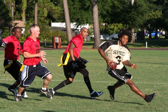 Brian Lewis (right), 16th Services Squadron intramural football team quaterback and coach, eludes a posse of 16th Logistics Readiness Squadron Accessories Flight POL players as he heads for the end zone. The SVS team 27-14 victory took their record for the season to 1–1. POLs’ defeat leaves them still searching for a win as they slip to 0–3. (U.S. Air Force Photograph by Senior Airman James Dickens) 
