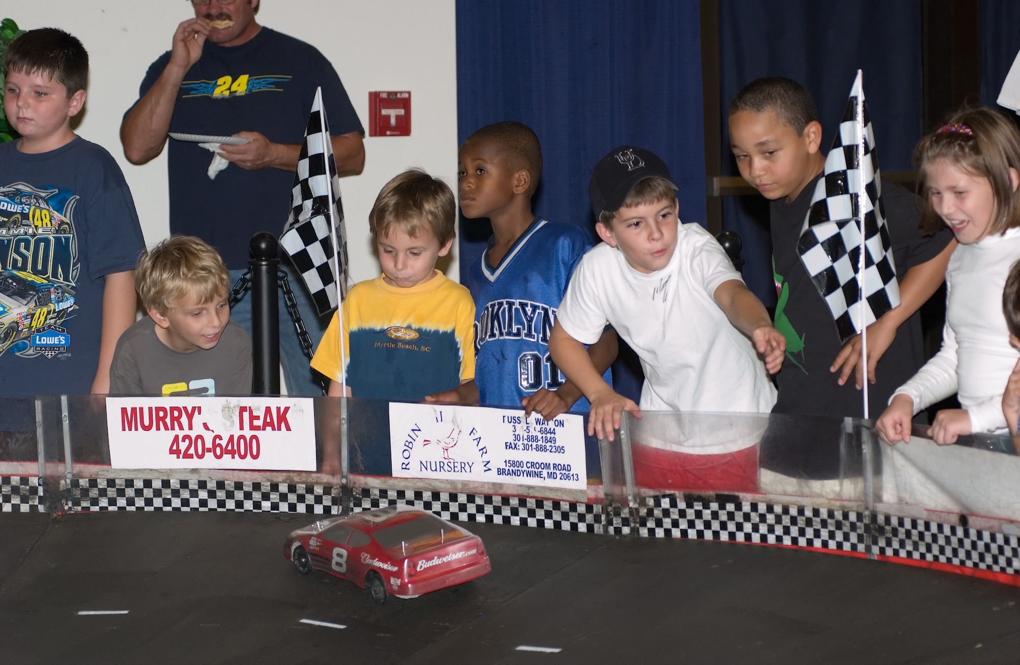 Children of Dover members race remote control cars around a track at the NASCAR Social Friday night at The Landings Club. The track allows participants to race custom designed cars around a 16-foot by 24-foot, high-banks race track. Other activities at the social included a race car simulator, moon bounces and give aways for attendees. The Air Mobility Command Matchup game Dover Air Force Base winners were also awarded cash and prizes at the end of the night. (U.S. Air Force photo/Jason Minto)