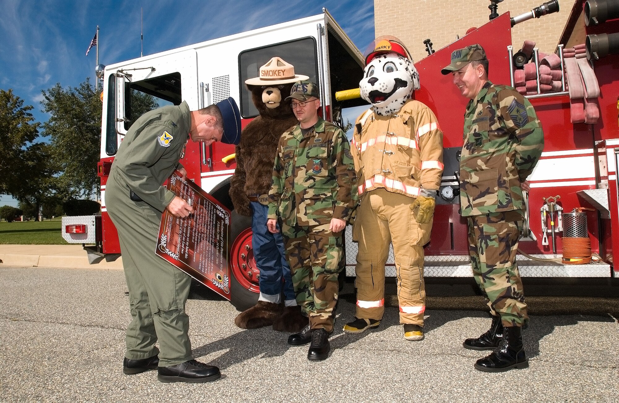 (Left to right) Col. Sam Cox, 436th Airlift Wing commander, signs the Fire Prevention Week Proclamation Sept. 21 here as Smokey the Bear; Tech. Sgt. Anthony Knight, 436th Civil Engineer Squadron; Sparky the Fire Dog; and Chief Master Sgt. Bruce Blodgett, 436th AW command chief, look on.