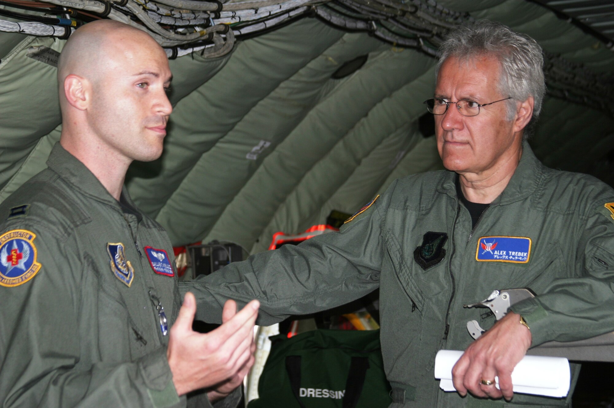 KADENA AIR BASE, Japan -- Alex Trebek, host of the Jeopardy game show, listens as U.S. Air Force Capt. Dallas Weills explains how Kadena's KC-135 aerial refueling aircraft can fly critical-care patients to hospitals in the United States.  Captain Weills is an instructor flight nurse with the 18th Aeromedical Evacuation Squadron.  During a two-day Jeopardy USO tour to Kadena March 30-31, Mr. Trebek and Jeopardy show staff also toured an F-22 stealth fighter, a KC-135 stratotanker, an E-3 AWACS (Airborne Warning and Control System), an F-15C fighter, and an HH-60 helicopter.  The F-22 is temporarily based at Kadena on its first overseas deployment from Langley Air Force Base, Va.  Kadena residents were allowed to try-out to be contestants on Jeopardy, as well.  (Air Force/Senior Airman Nestor Cruz)