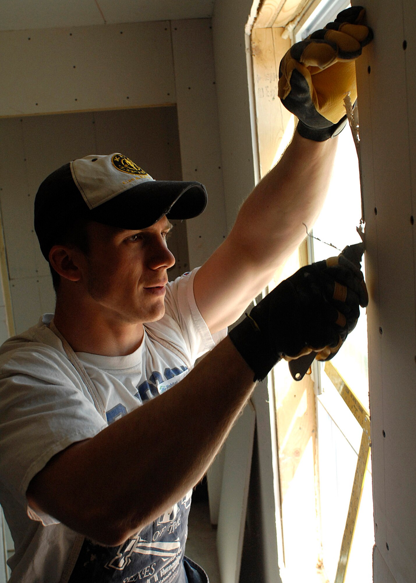 U.S. Air Force Academy Cadet Jordan Ostwald cuts away sheetrock at a Habitat for Humanity home in Tome, N.M. Cadet Ostwald is joining a group of approximately 10 other cadets who are using their spring break to volunteer rather than traveling and relaxing. (U.S. Air Force photo/Todd Berenger.)