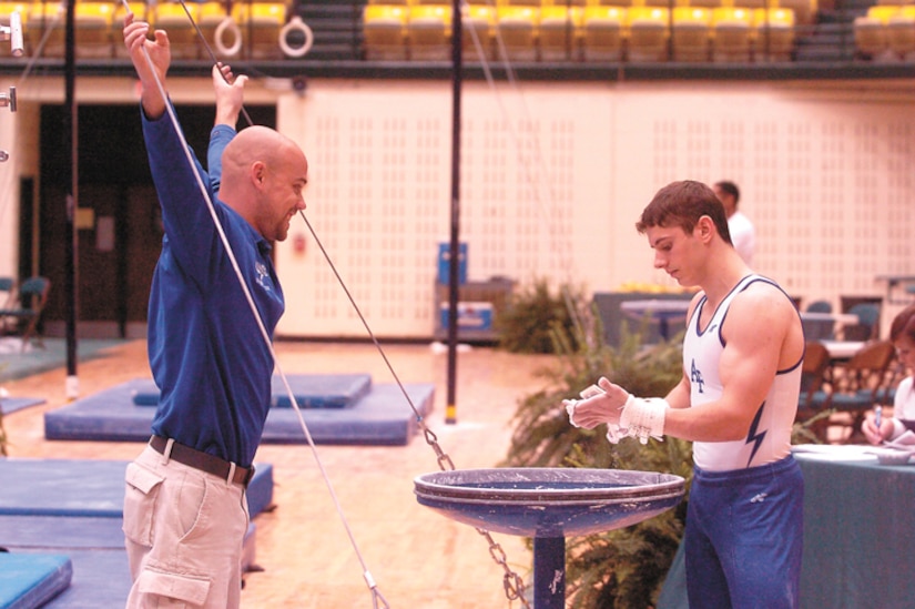 Falcons' assistant coach Brett McClure offers a word of encouragement to Air Force Academy junior Greg Stine as he chalks up his hands prior to his next event during the United States of America Gymnastics championships held at the College of Wililam & Mary in Williamsburg, Va., March 24 and 25. (Military Newspapers of Virginia photo/Harry Gerwien)