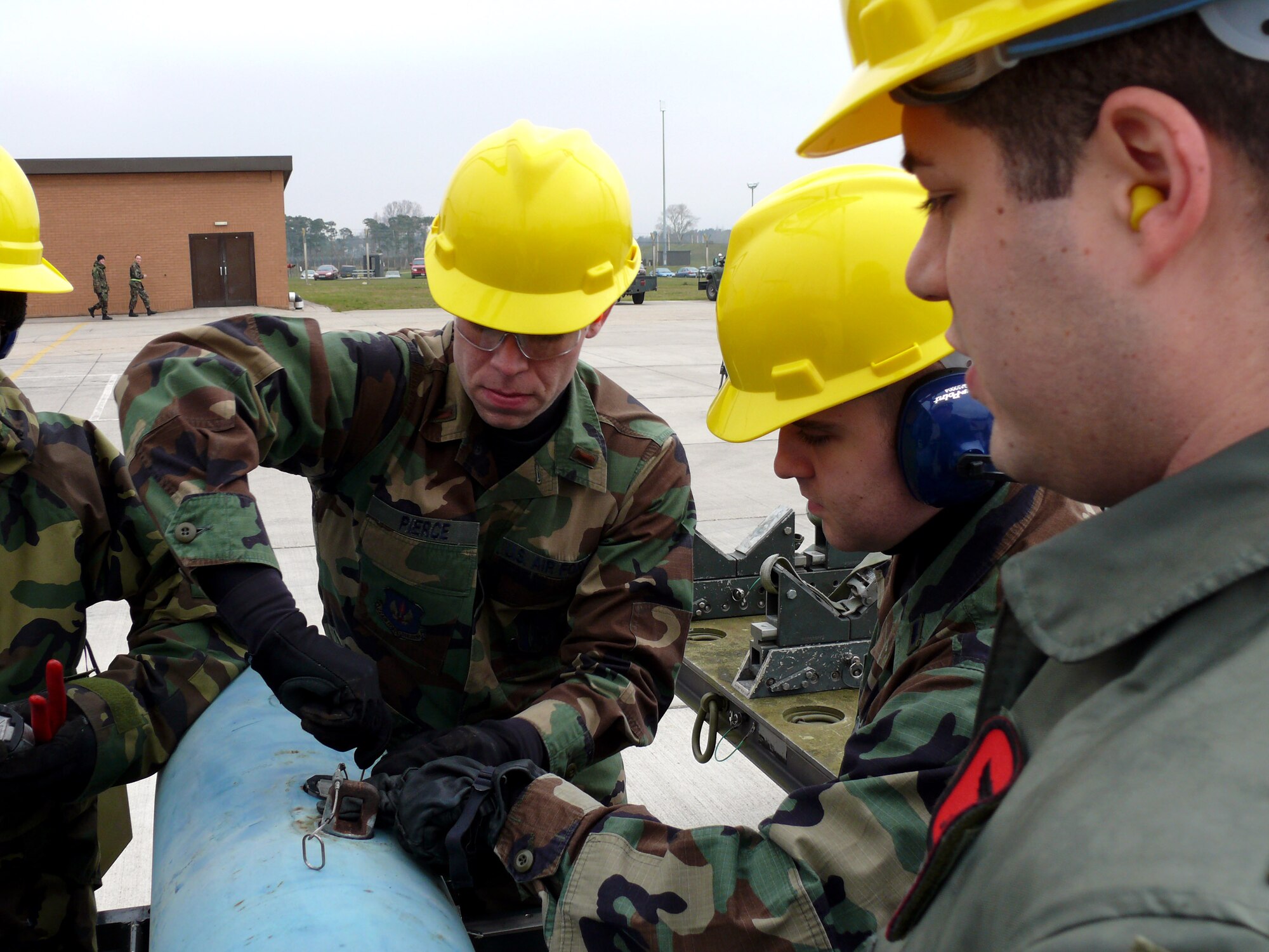 Second Lt. Adam Pierce (left) works on a Mark 82 bomb while 1st Lt. Brian Scozzaro (center) and 1st Lt. Christopher Jones look on. The three took part in a one-day course to better understand what munition specialists have to go through to get bombs ready for a mission. (U.S. Air Force photo/Tech. Sgt. Scott Wakefield) 

