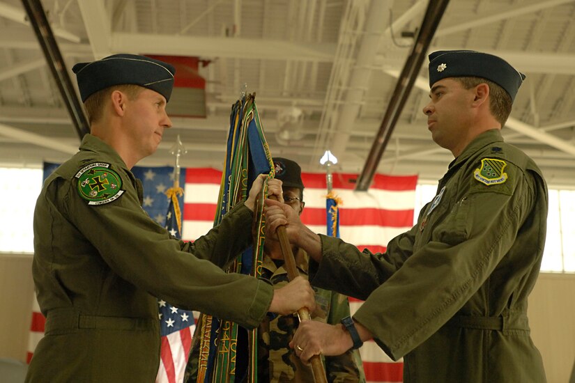 Col. Tom Bergeson, 1st Operations Group commander, passes the guidon to Lt. Col. Kevin Fesler, the new 94th Fighter Squadron commander, during the change of command ceremony here March 23. (U.S. Air Force photo/Airman 1st Class Vernon Young) 