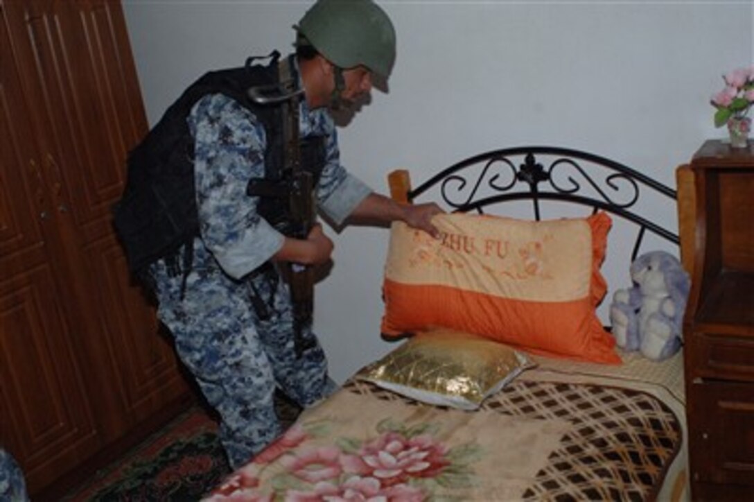 A member of 3rd Battalion, 8th Brigade, 2nd Iraqi National Police Division, searches a home in the Rusafa area of East Baghdad, Iraq, March 27, 2007, during a combined cordon and search operation with U.S. Army soldiers.