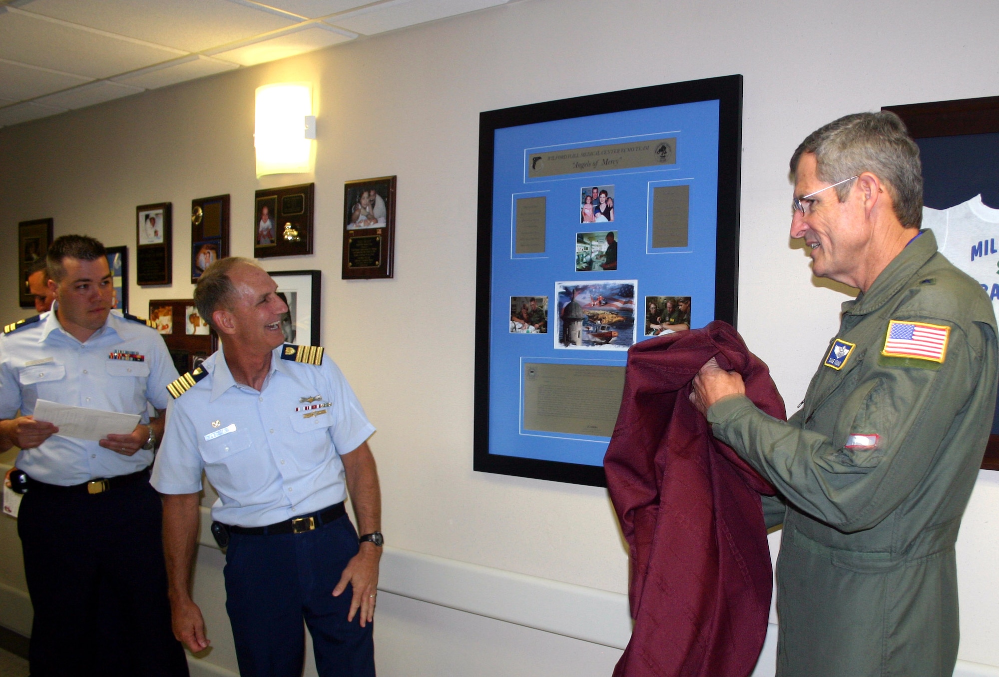 A plaque thanking the 59th Medical Wing's Extracorporeal Membrane Oxygenation team is unveiled by Brig. Gen. (Dr.) David Young (right) and Coast Guard Capt. James Tunstall.  Captain Tunstall and Coast Guard Lt. Seth Parker (left rear) traveled from San Juan, Puerto Rico, to Wilford Hall Medical Center at Lackland Air Force Base, Texas, to present the plaque and thank the ECMO team for saving the life of baby Stuart Parker, Lieutenant Parker's son.  General Young is the 59th MDW commander.  Captain Tunstall is the San Juan Sector 7 Coast Guard commander.  (U.S. Air Force photo/Master Sgt. Kimberly Spencer)