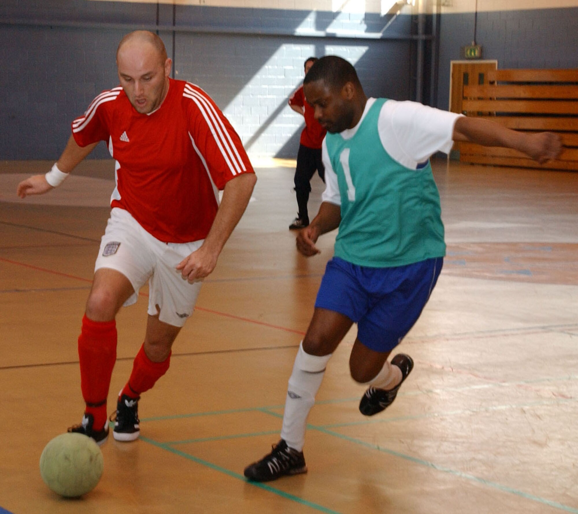 Pete Webb, 727th Air Mobility Squardron, moves past the 100th Logistics Readiness Squardron's Leighton Powell April 2, during an indoor soccer game at the Northside fitness center. (U.S. Air Force photo by Airman Brad Smith)