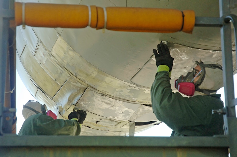 Senior Airman Chris Taylor and Senior Airman Randall Pearce, 315th Maintenance Squadron, remove paint from the left engine of the C-124 Globemaster II at the Charleston AFB Air Park April 2. (U.S. Air Force photo/Staff Sgt. April Quintanilla)