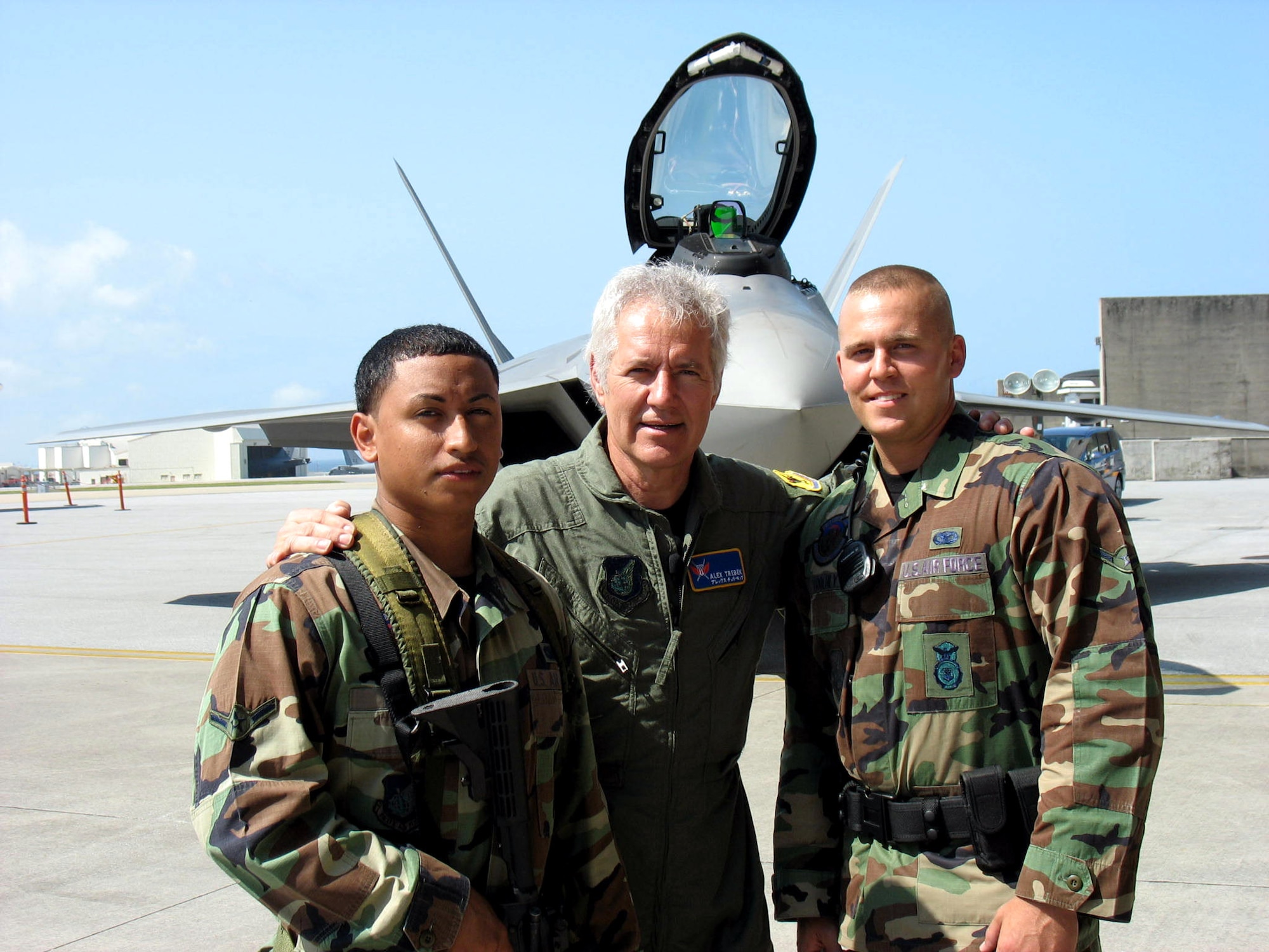 Alex Trebek poses with Airmen Jake Froehly and Adam Flores during a "Jeopardy" game show USO tour of Japan March 31 at Kadena Air Base, Japan. Both Airmen are assigned to the 18th Security Forces Squadron at Kadena AB. During a two-day trip to Kadena AB March 30 and 31, Mr. Trebek and "Jeopardy" show staff toured an F-22 Raptor, KC-135 Stratotanker, E-3 Sentry, F-15 Eagle, and an HH-60 Pave Hawk during the two-day visit to Kadena AB. The F-22 is temporarily based at Kadena AB on its first overseas deployment from Langley Air Force Base, Va. Kadena AB residents were allowed to try-out to be contestants on "Jeopardy." (U.S. Air Force photo/Senior Master Sgt. Kenneth Fidler)