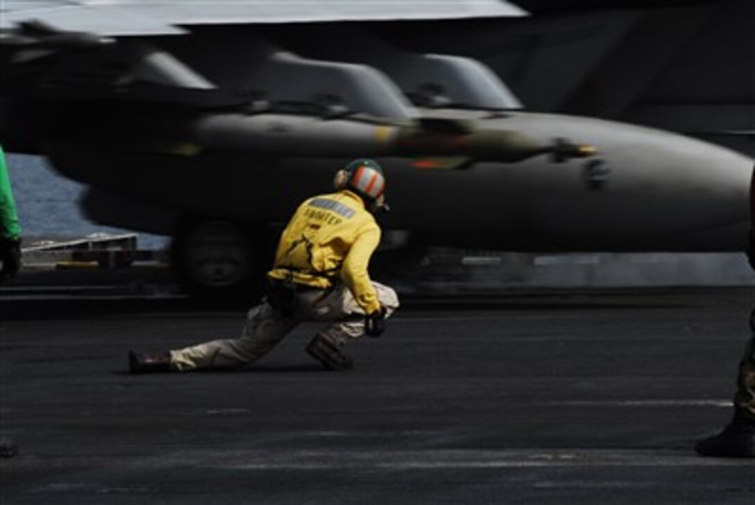 A U.S. Navy aircraft launch officer ducks down to allow the wing of an F/A-18F Super Hornet to pass over him as the aircraft catapults from the flight deck of the aircraft carrier USS John C. Stennis (CVN 74) on March 28, 2007.  The Stennis Carrier Strike Group and its embarked Carrier Air Wing 9 are conducting a dual-carrier exercise with the Eisenhower Carrier Strike Group and Carrier Air Wing 7 in the Persian Gulf.  