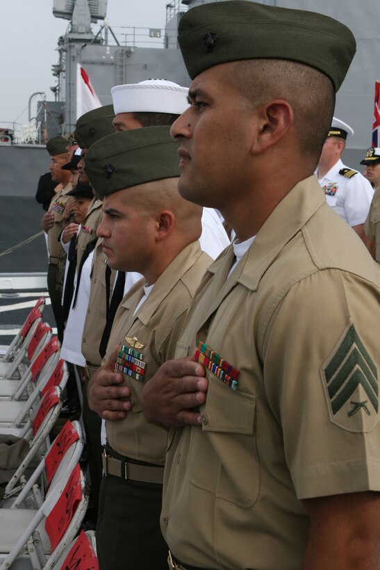 Sgt. Juan Bravo, freight specialist, traffic management office and a native of Mexico and GySgt. Boris Peredo, squadron first sergeant, MALS-11 and a native of Bolivia, join 57 other service members in reciting the Pledge of Allegiance after receiving their certificate of naturalization onboard the USS Cleveland, April 4, 2007.