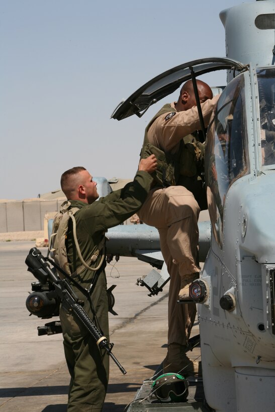 Lance Cpl. Joseph L. Yawn, an airframes mechanic with Marine Light Attack Helicopter Squadron 367 'Scarface," helps Capt. Henry Doleberry, co-pilot of a AH-1W Super Cobra, enter the helicopter as the siren blares signifying a casualty evacuation mission.  The Super Cobras provide security for the Ch-46 Sea Knights that serve as the casualty evauation helicopters.