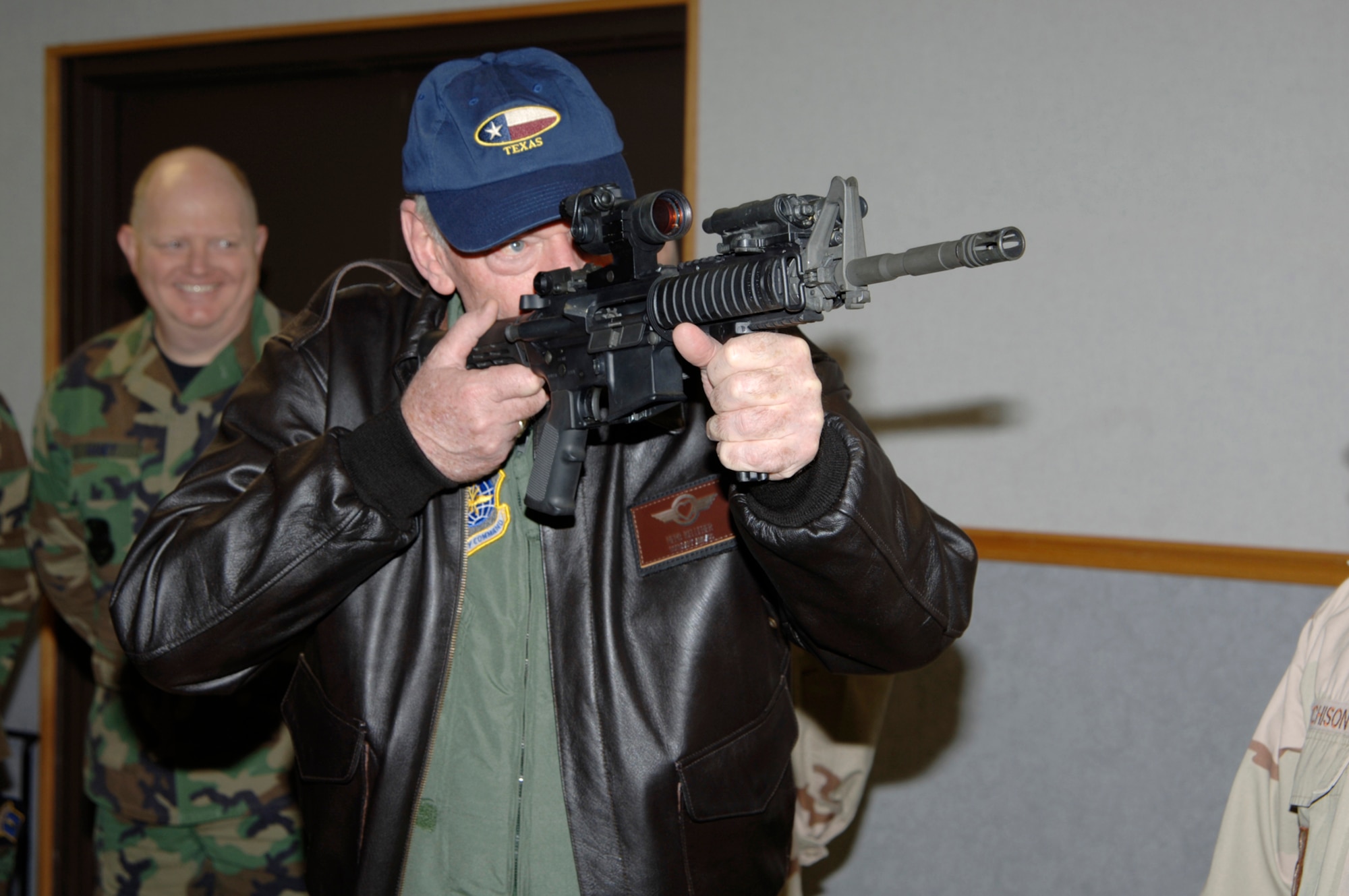 Herb Kelleher, a founder and executive chairman of Southwest Airlines, holds an M-4 rifle while looking through an M-68 optic sight at the firearms training simulator, during a visit to McConnell Air Force Base, Kan., April 5, with Gen. Duncan J. McNabb, commander Air Mobility Command, Scott Air Force Base, Ill. (Air Force photo by Senior Airman Jamie Train 22nd Communications Squadron)
