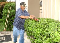 Carlos Moreno manicures the hedges in front of the 37th Civil Engineer Squadron. He and other Team Lackland members spent March 30 tidying up the base as part of this year's annual Beautification Project. The 37th CE provided gardening tools and numerous plants and flowers for the event. (USAF photo by Sid Luna)                                