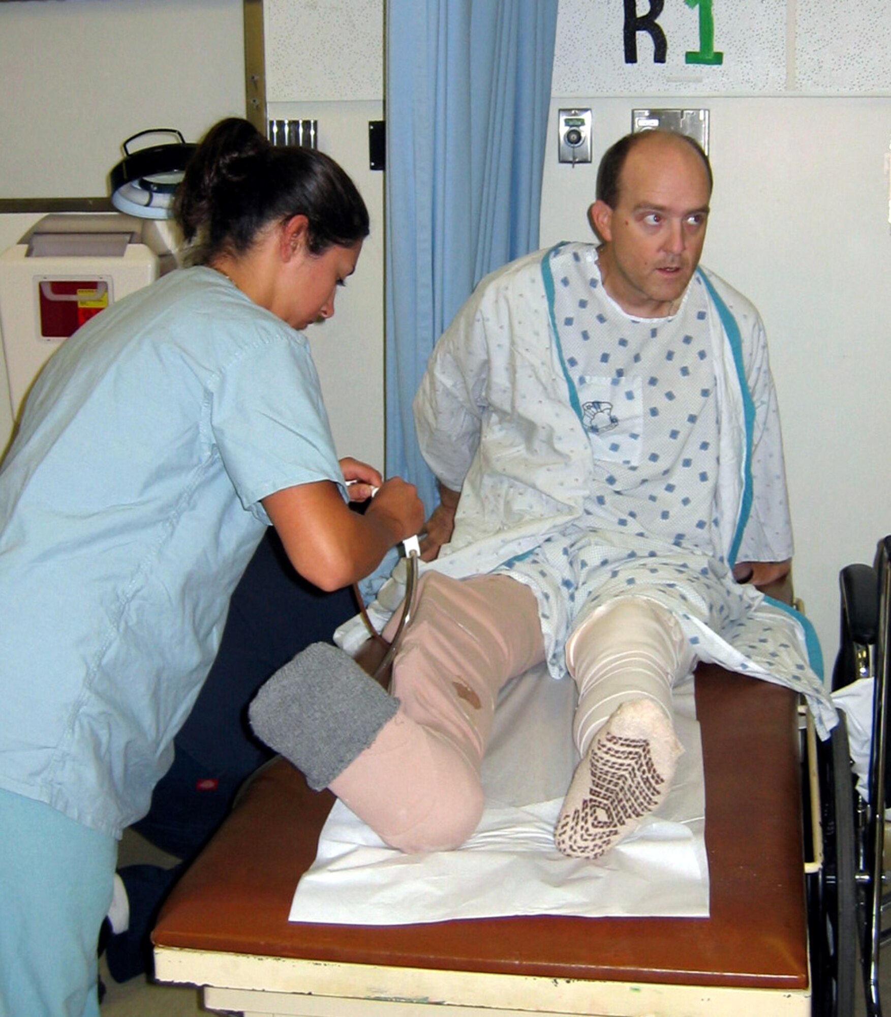 Senior Airman Renee Brandt hooks up a wound-vac pump to Maj. Mathew Conlan at Wilford Hall Medical Center, Lackland Air Force Base, Texas, July 7, 2005. Major Conlan was receiving care following orthopedic surgery for complex lower extremity injuries received while he was deployed to Bagram Air Base, Afghanistan. Major Conlan was injured by a landmine blast while serving as the commander of the 455th Expeditionary Civil Engineer Squadron at Bagram. Airman Brandt is a medical technician with the 59th Medical Wing.  (U.S. Air Force photo/Becky Conlan) 