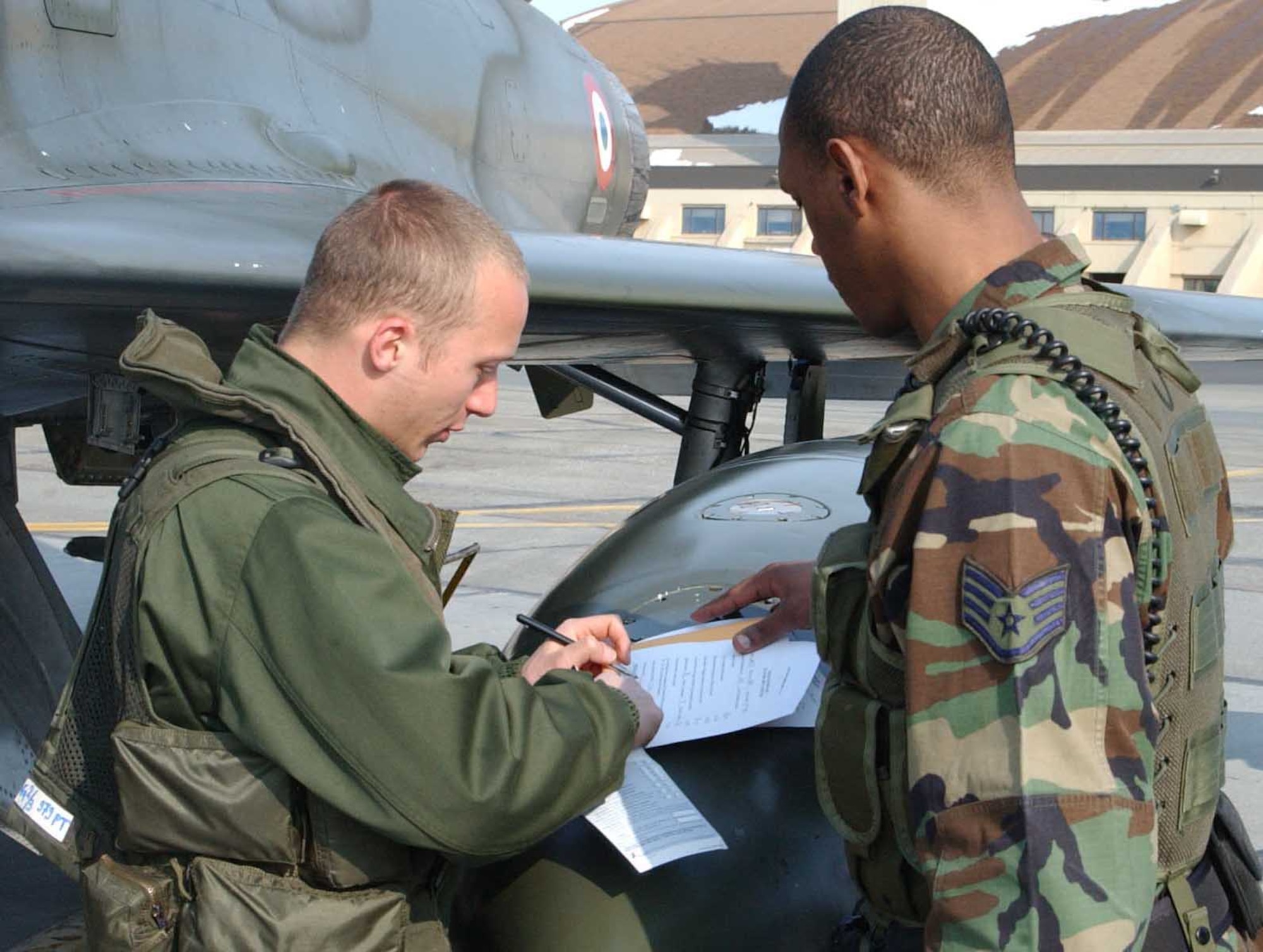 EIELSON AIR FORCE BASE, ALASKA -- Staff Sgt. Cedric Hughes, 354th Security Forces Squadron, helps 2nd Lt. Olivier Zemauli, a French Air Force pilot, with customs paperwork April 3 on the flightline. Security forces Airmen are certified to clear military aircraft and personel through customs when arriving at Eielson from another country. More than 1,300 air force personnel from the U.S., France and Australia are arriving in Alaska this week to take part in Red Flag-Alaska, a series of training exercises that include war games with allies and mock enemies. (U.S. Air Force photo by Senior Airman Justin Weaver).
