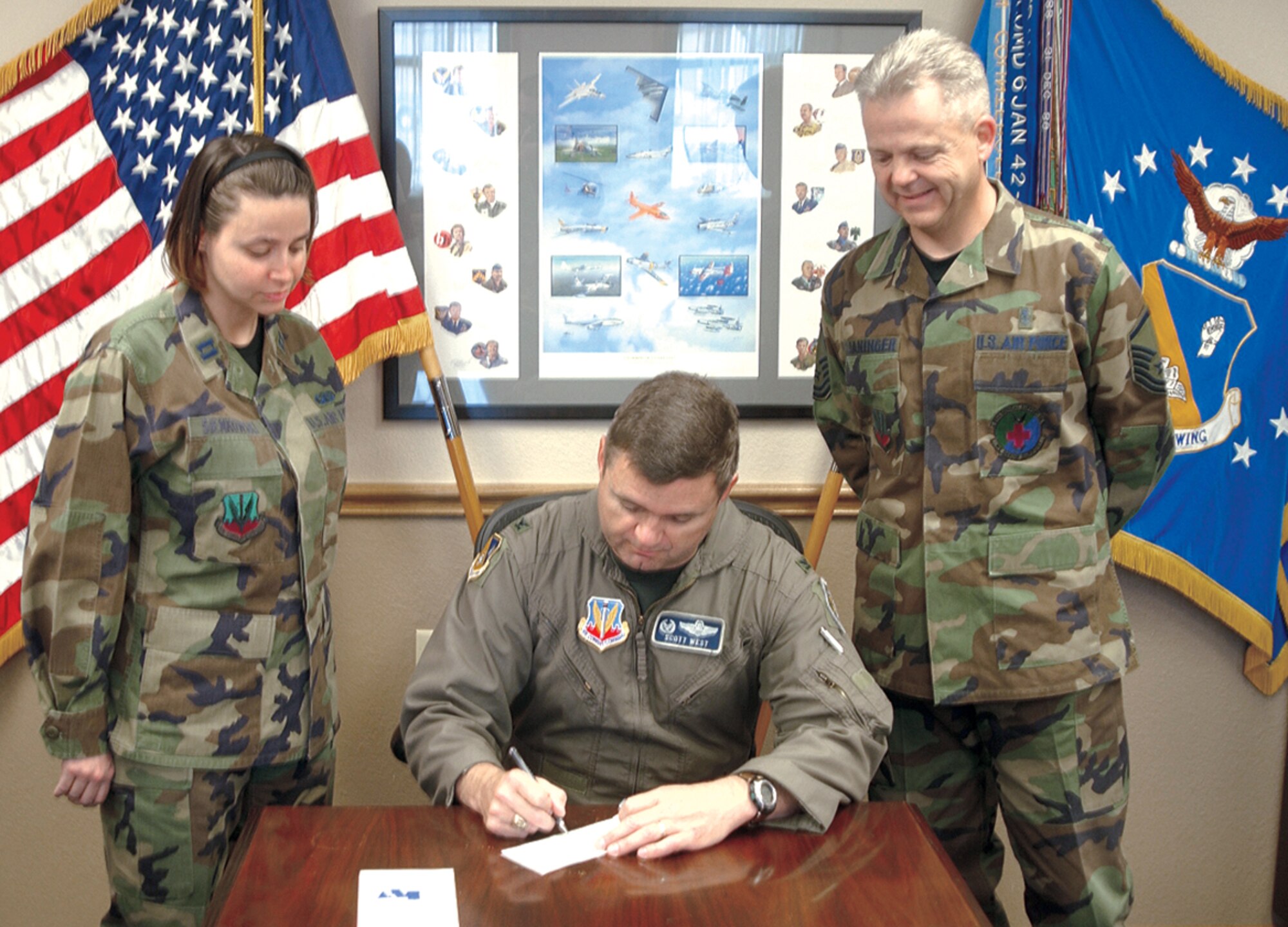 Col. Scott West, 27th Fighter Wing commander, makes a donation to the Air Force Assistance Fund on April 4. AFAF program managers Capt. Christine Seinkowski, 27th Comptroller Squadron, and Master Sgt. Fred Cloaninger, 27th Medical Group, stand by ready to accept the check. (Air Force photo by Airman 1st Class Thomas Trower)                             