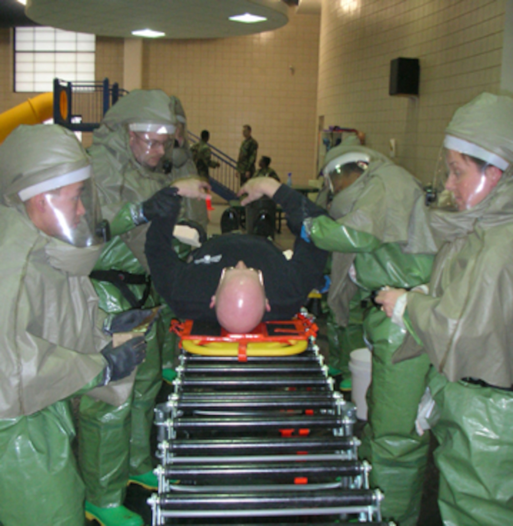 Memebers of the 319th Medical Group dressed in protective plastic suits practice decontaminating Col. Robert Quinn, 319 MDG commander, during an exercise at the fitness center's pool March 31. The pool is the alternate decontamination site during the brutally cold winter months here. (Courtesy photo)