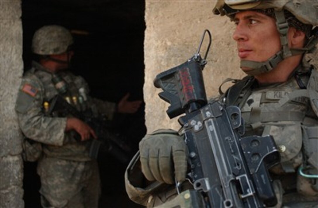 U.S. Army Spc. Jay Kilpatrick (right) and Sgt. Patrick Oglesbee provide security for their fellow soldiers while they take a quick break in the shade during a search for weapons caches in Baghdad, Iraq, on March 29, 2007.  Kilpatrick and Oglesbee are assigned to the 1st Battalion, 23rd Infantry Regiment, 2nd Infantry Division.  