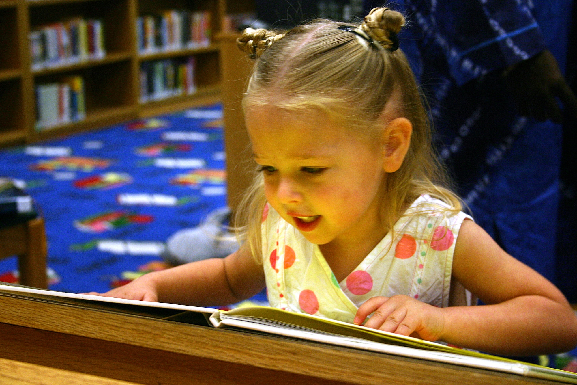LAUGHLIN AIR FORCE BASE -- Lili Bragg, daughter of Larissa and 2nd Lt. Joel Bragg, 85th Flying Training Squadron, reads an Easter book after story time at the base librayr Friday.  (U.S. Air Force photo by Airman Sara Csurilla)