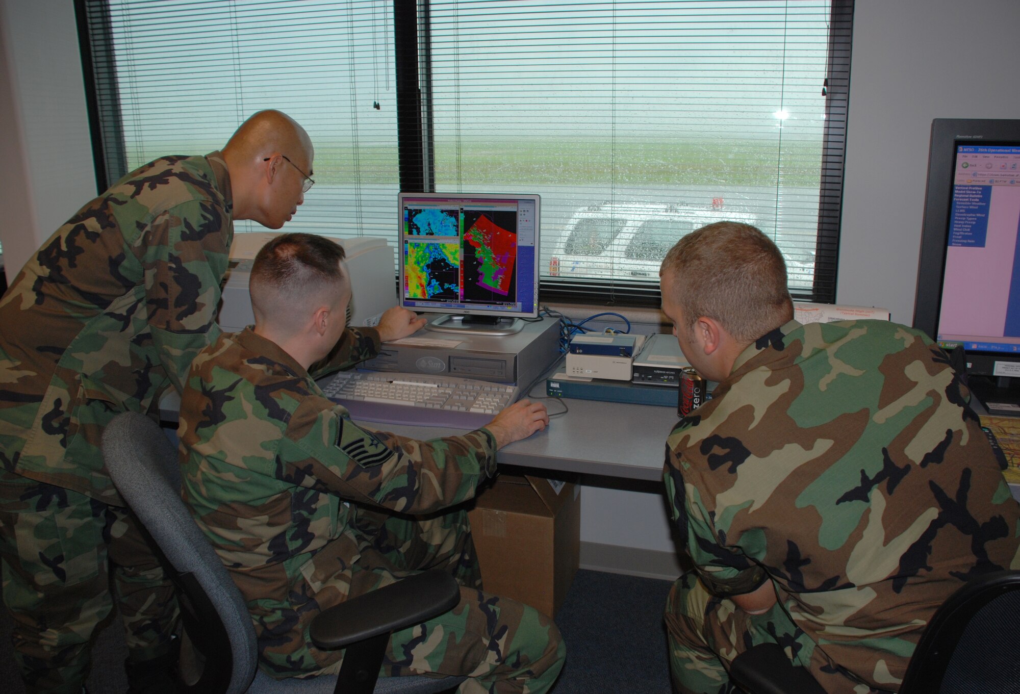 Members of the 80th Operations Support Squadron's weather operations flight look over incoming data as severe weather assaults the base outside March 30. (U.S. Air Force photo/Airman 1st Class Jacob Corbin)