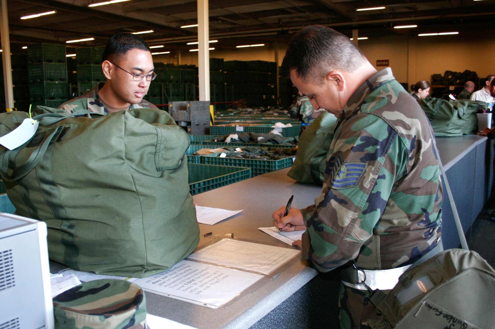 Airman 1st Class Jonathan Malumay, 60th Logistics Readiness Squadron, checks over an inventory sheet for a C-bag being provided to Tech. Sgt. Ruben Quinterofarias, 60th Services Squadron, during the Crisis Look 07-02 deployment exercise held on Travis Air Force Base, Calif. (U. S. Air Force photo Laura Fentress)