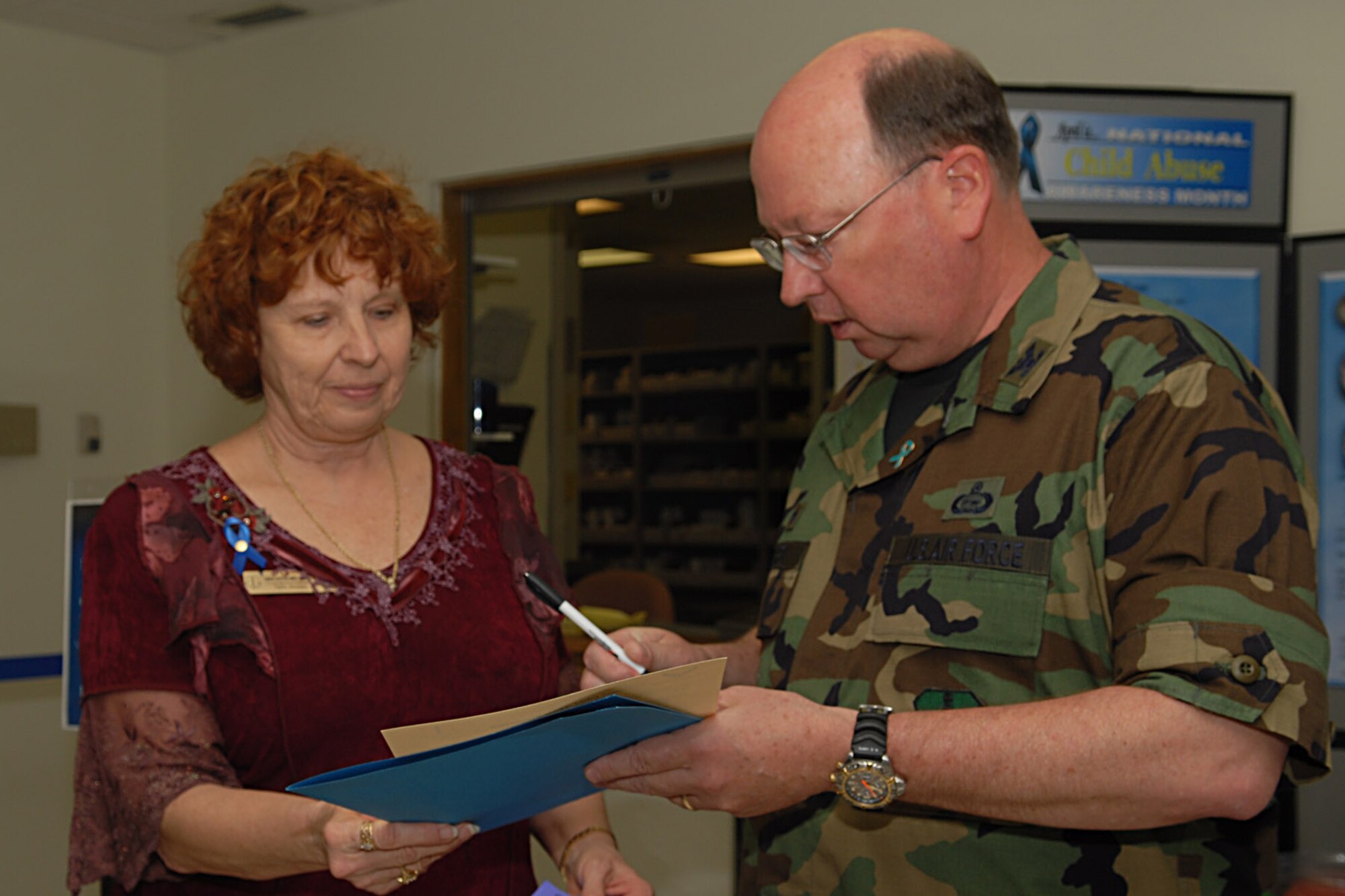 Col. Richard Ayres, 17th Training Wing commander (right), signs the National Child Abuse Prevention Awareness Proclamation in the lobby of the 17th Medical Group, while Karen Bartholomeo looks on. April is both the Month of the Military Child and National Child Abuse Prevention Month. (U.S. Air Force photo by Airman 1st Class Kamaile Chan)
