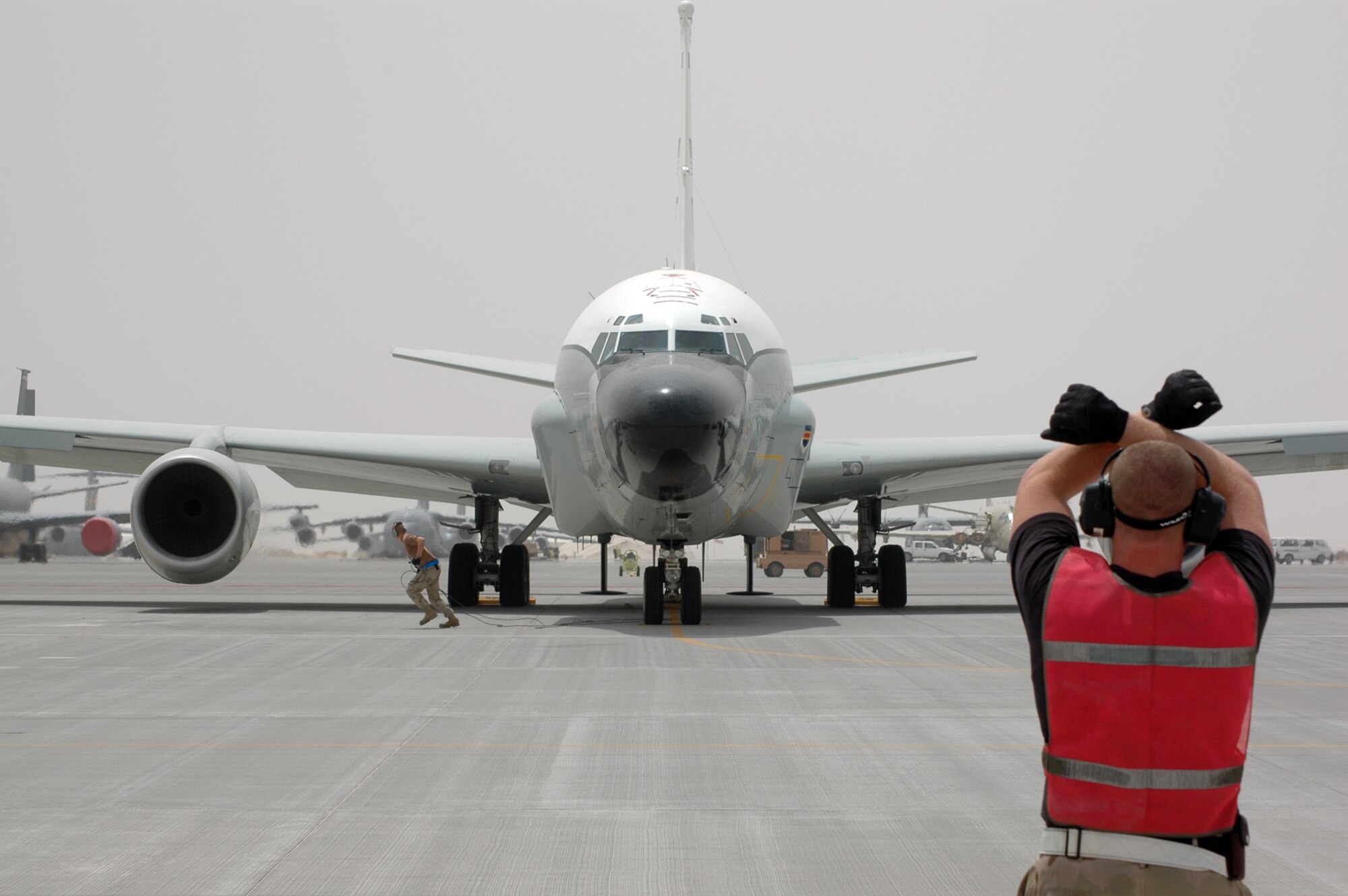 Staff Sgt. Cheyenne Bode, 379th Expeditionary Aircraft Maintenance Squadron 55th Aircraft Maintenance Unit electrical and environmental craftsman stands ready to marshal a RC-135 out from its parking space for a mission in Southwest Asia. (U.S. Air Force photo by Senior Airman Erik Hofmeyer)