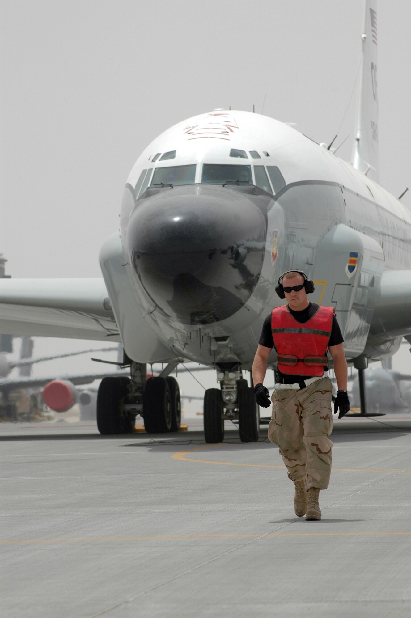 Staff Sgt. Cheyenne Bode, 379th Expeditionary Aircraft Maintenance Squadron 55th Aircraft Maintenance Unit electrical and environmental craftsman walks out to marshal the RC-135 from its parking space for a mission in Southwest Asia. (U.S. Air Force photo by Senior Airman Erik Hofmeyer)
