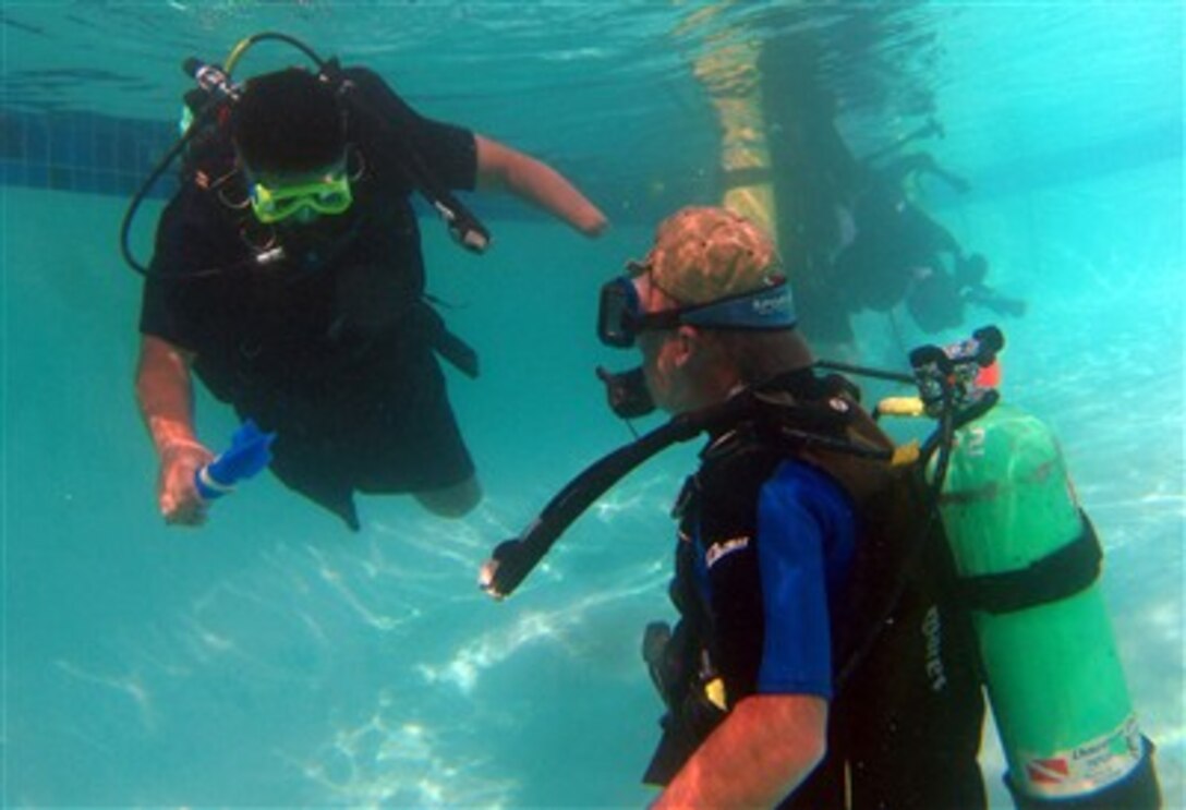 Triple amputee, U.S. Army Sgt. Hilario Bermanis II, wounded in Iraq on June 10, 2003, swims with a scuba diving instructor during the National Disabled Veterans Winter Sports Clinic in Snowmass, Colo., April 2, 2007.