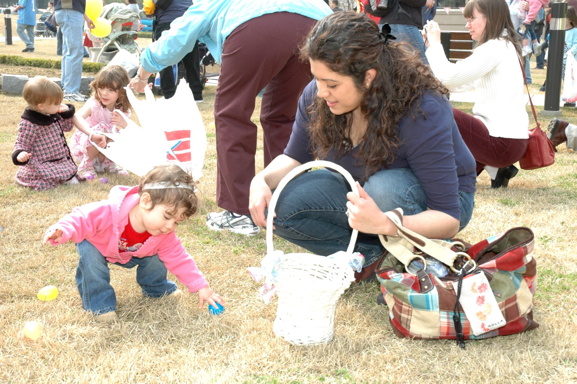 OSAN AIR BASE, Republic of Korea --  Emma Burger, 1-year-old, picks up a plastic egg while her mother Melissa Burger holds her Easter basket. The 51st Services Squadron hosted the Easter Egg Hunt on Saturday at Turumi Park. (U.S. Air Force photo by Staff Sgt. Benjamin Rojek)