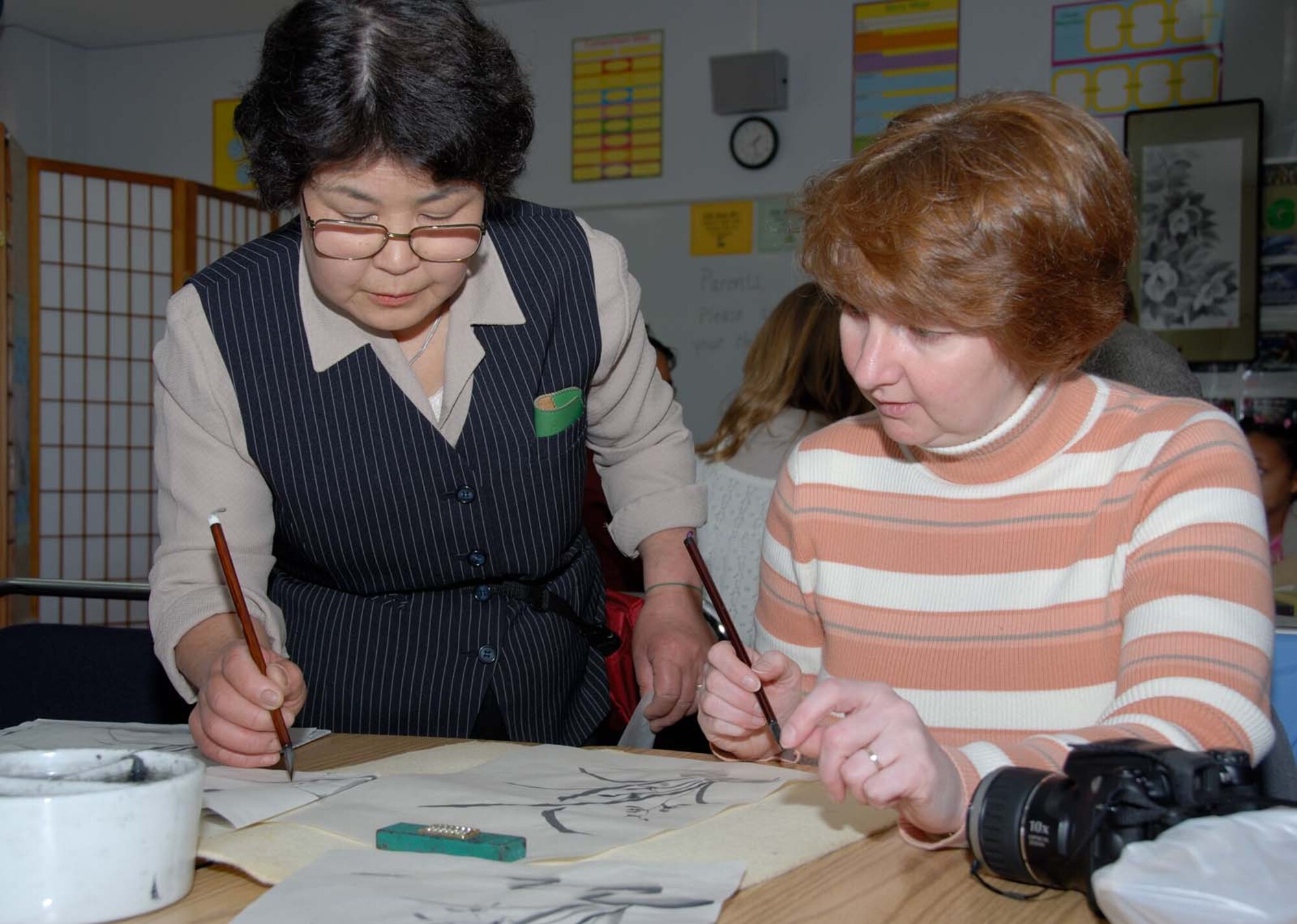 Misawa Air Base, Japan -- Eiko Takada teaches Elke Hanson Bokuga Brush Painting during the 20th Annual Japan Day Celebration at Misawa Air Base, Japan on April 7, 2007.  Elke Hanson is the spouse of an Army and Air Force Exchange Services employee.  Japan Day is held annually to support Japanese/American relations.  During the day, Americans are given a chance to see traditional Japanese customs without having to leave the base.  U.S. Air Force photo by Senior Airman Laura R. McFarlane.